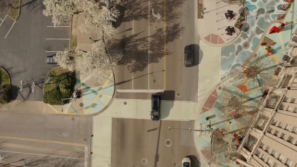 Overhead view of a city intersection with vehicles and pedestrians crossing